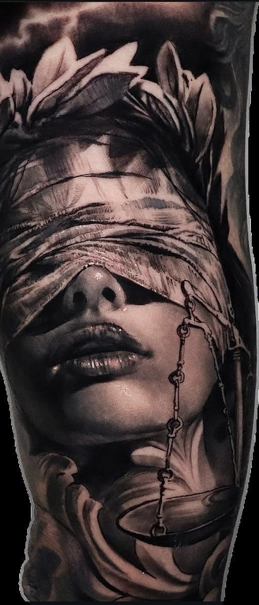 Black and grey realism tattoo of a blindfolded woman wearing a laurel wreath.