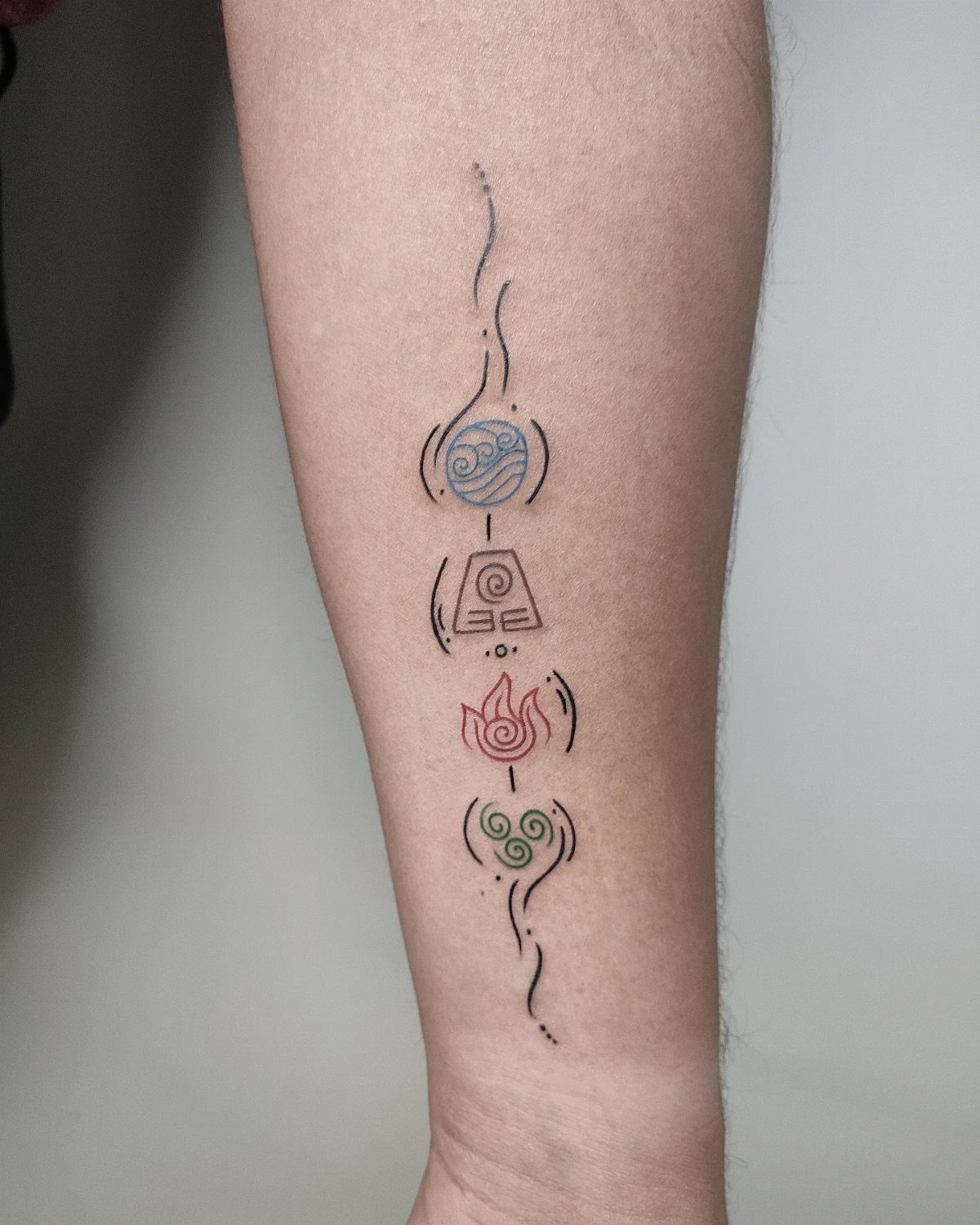 5 Avatar Elements Tattoo Ideas for a Clean, Story-Driven Design 5 A vertical forearm tattoo featuring four elemental symbols connected by thin black flowing lines.