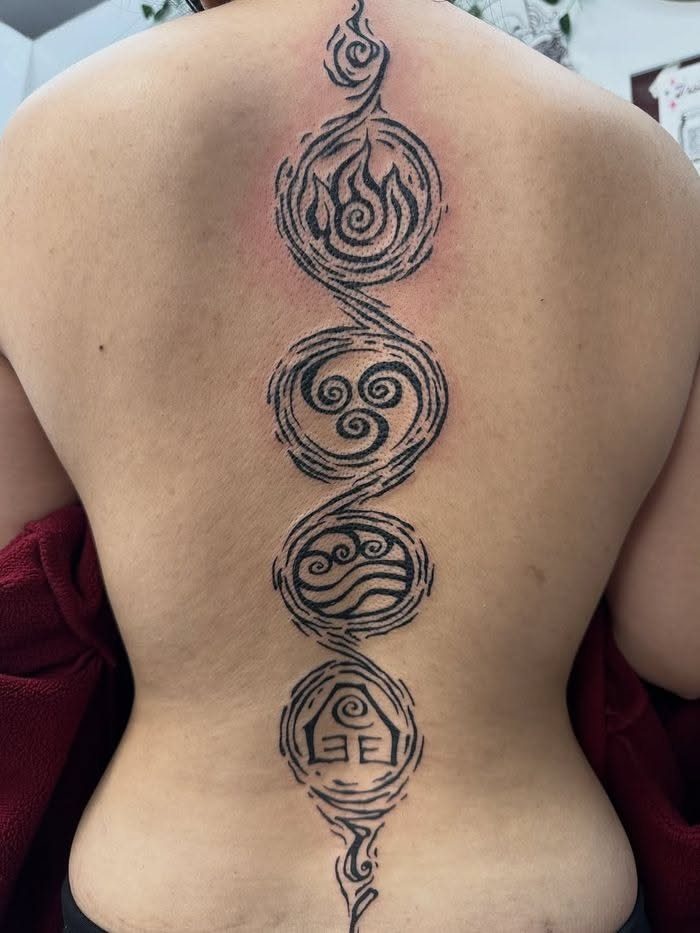 5 Avatar Elements Tattoo Ideas for a Clean, Story-Driven Design 3 Black ink elemental symbols tattooed in a vertical line down a person's spine.