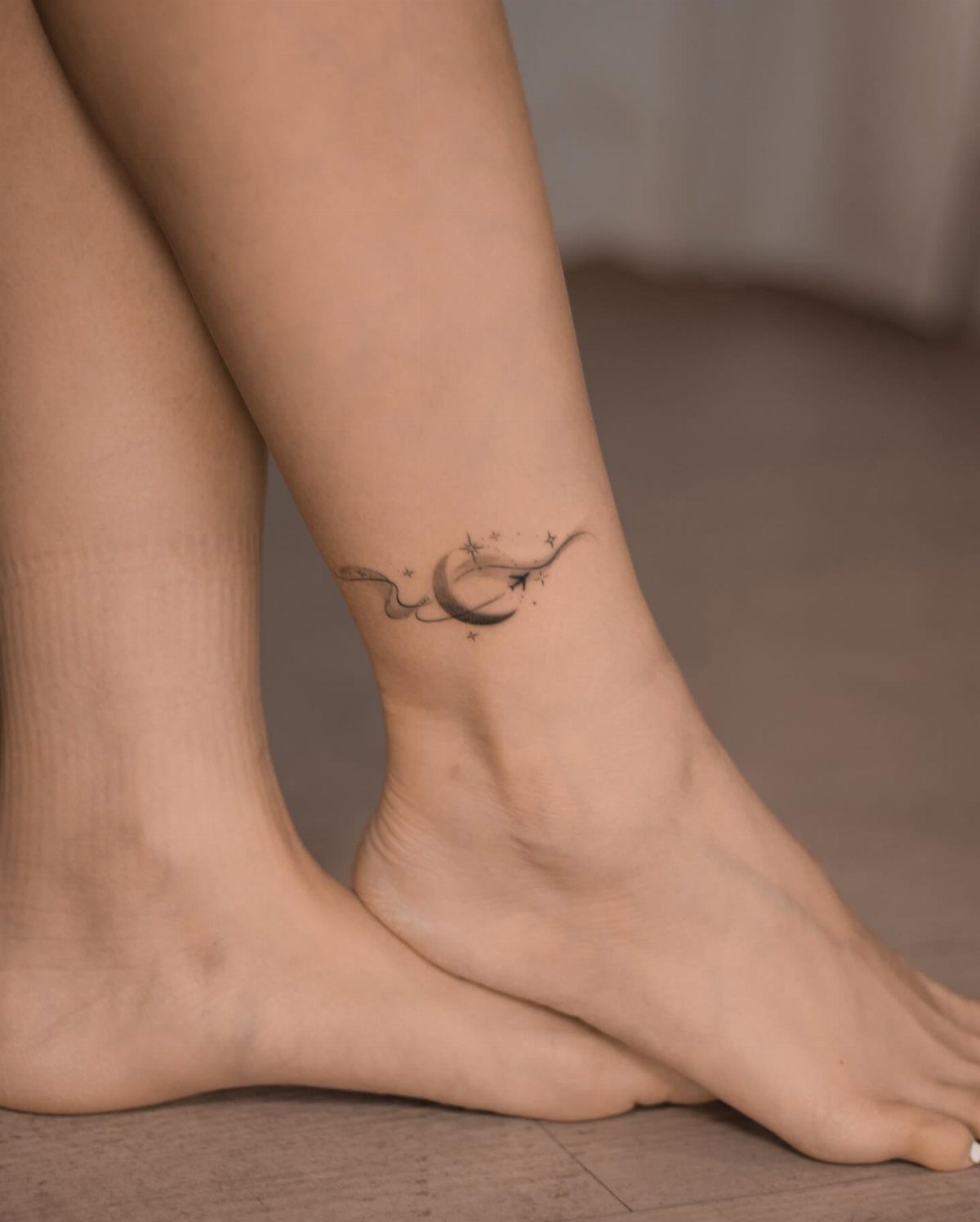 7 Feminine Ankle Tattoos for Every Style 3 A delicate crescent moon and stars tattoo on a person's ankle.