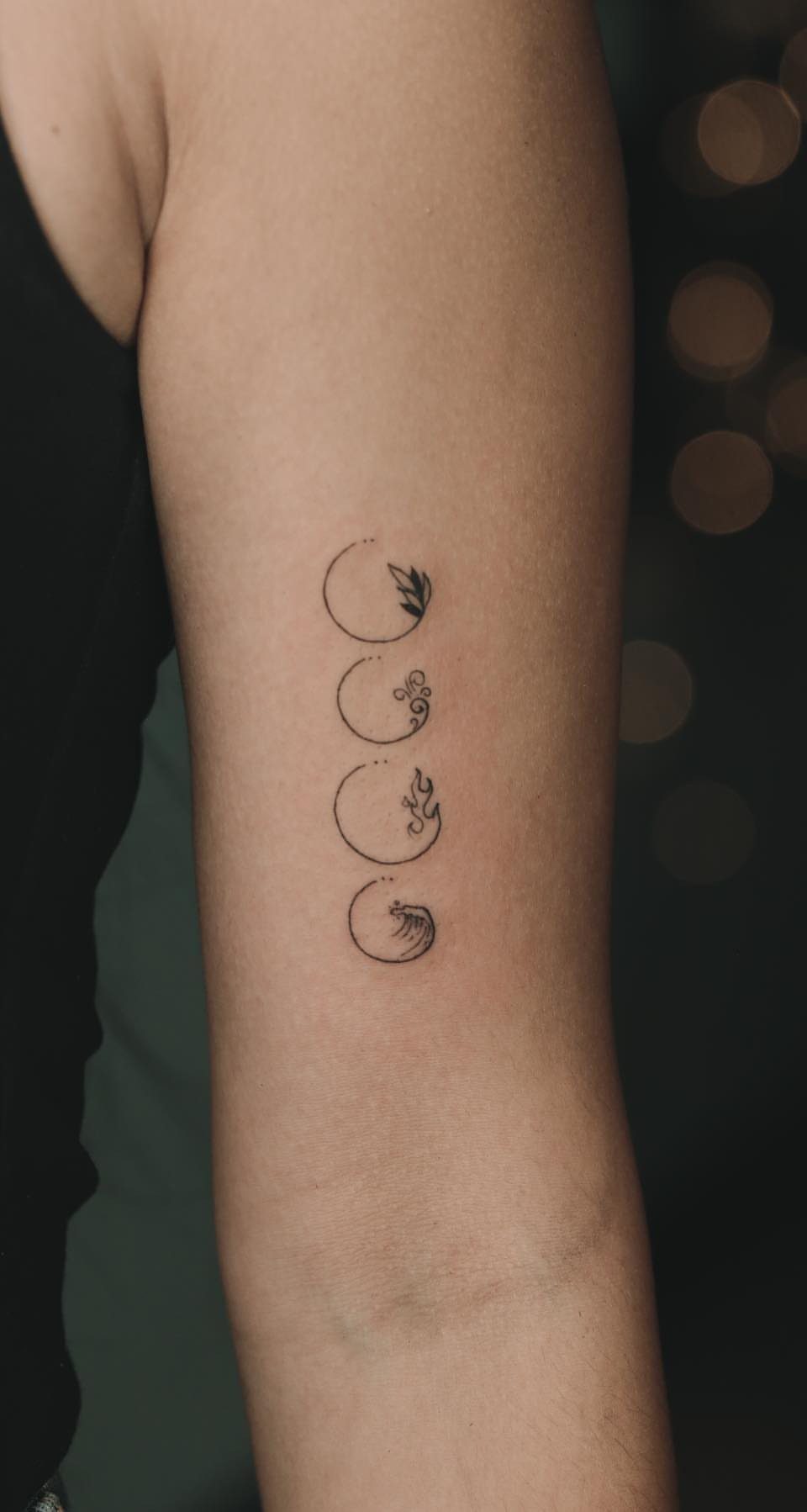 Four Elements Tattoo Design: 7 Styles That Hold Their Own 2 Four minimalist black ink elemental symbol tattoos arranged vertically on a person's arm.