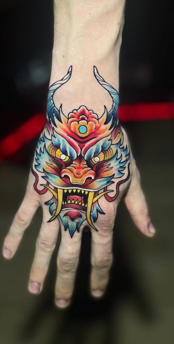 A colorful Japanese dragon tattoo covering the back of a person's hand.