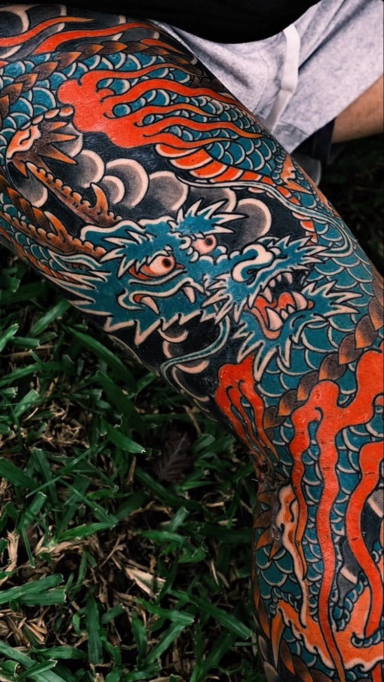 Japanese Dragon Tattoos: 19 Designs With Meaning and Style 7 A large, colorful Japanese dragon tattoo with blue and orange ink on a person's leg.