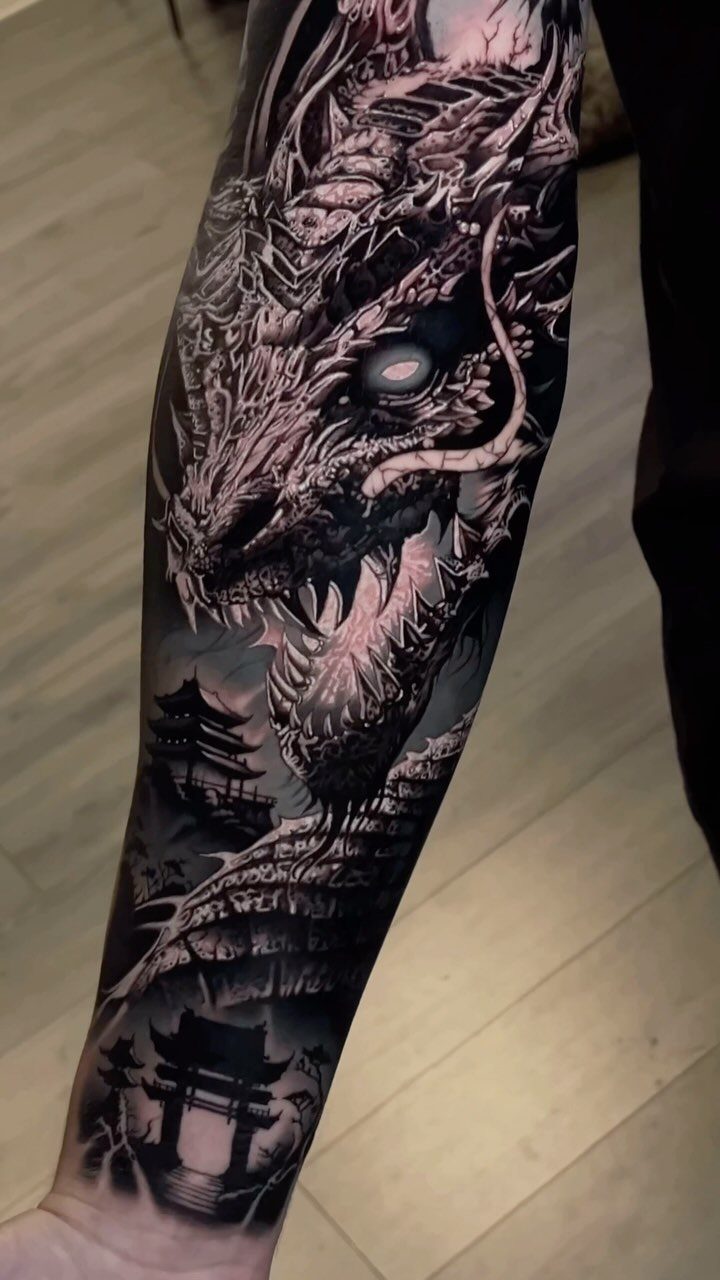 Japanese Dragon Tattoos: 19 Designs With Meaning and Style 19 A detailed black and grey Japanese dragon tattoo covering a person's entire forearm.