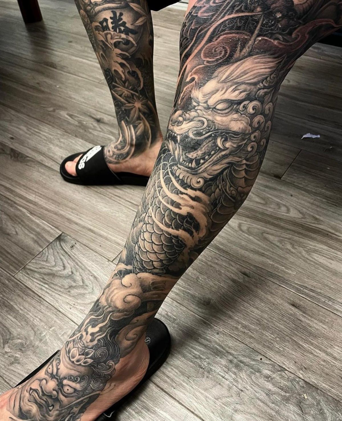 Japanese Dragon Tattoos: 19 Designs With Meaning and Style 16 Detailed black and grey Japanese dragon tattoos covering a person's legs and feet.