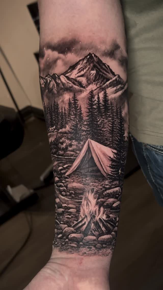 10 Mountain Landscape Tattoo Ideas For Your Next Ink 7 A detailed black and grey mountain landscape tattoo covering a person's forearm.