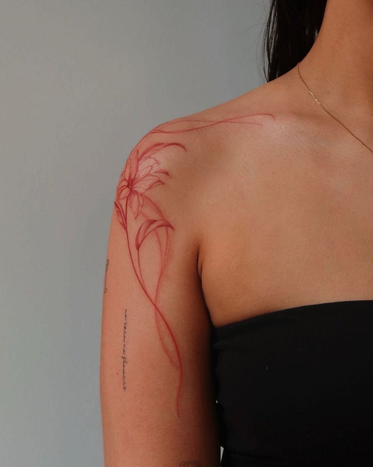 8 Red Fine Line Tattoo Ideas for Minimal Statement 2 A delicate red fine line flower tattoo on a person's shoulder and upper arm.