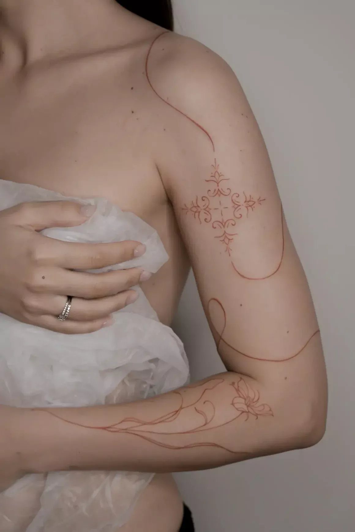 8 Red Fine Line Tattoo Ideas for Minimal Statement 5 Red fine line tattoos of ornamental patterns and flowing vines on a person's arm.