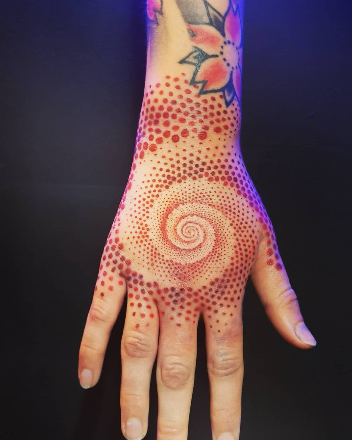 8 Red Fine Line Tattoo Ideas for Minimal Statement 8 A hand with a red dotwork tattoo forming a spiral pattern on the back.