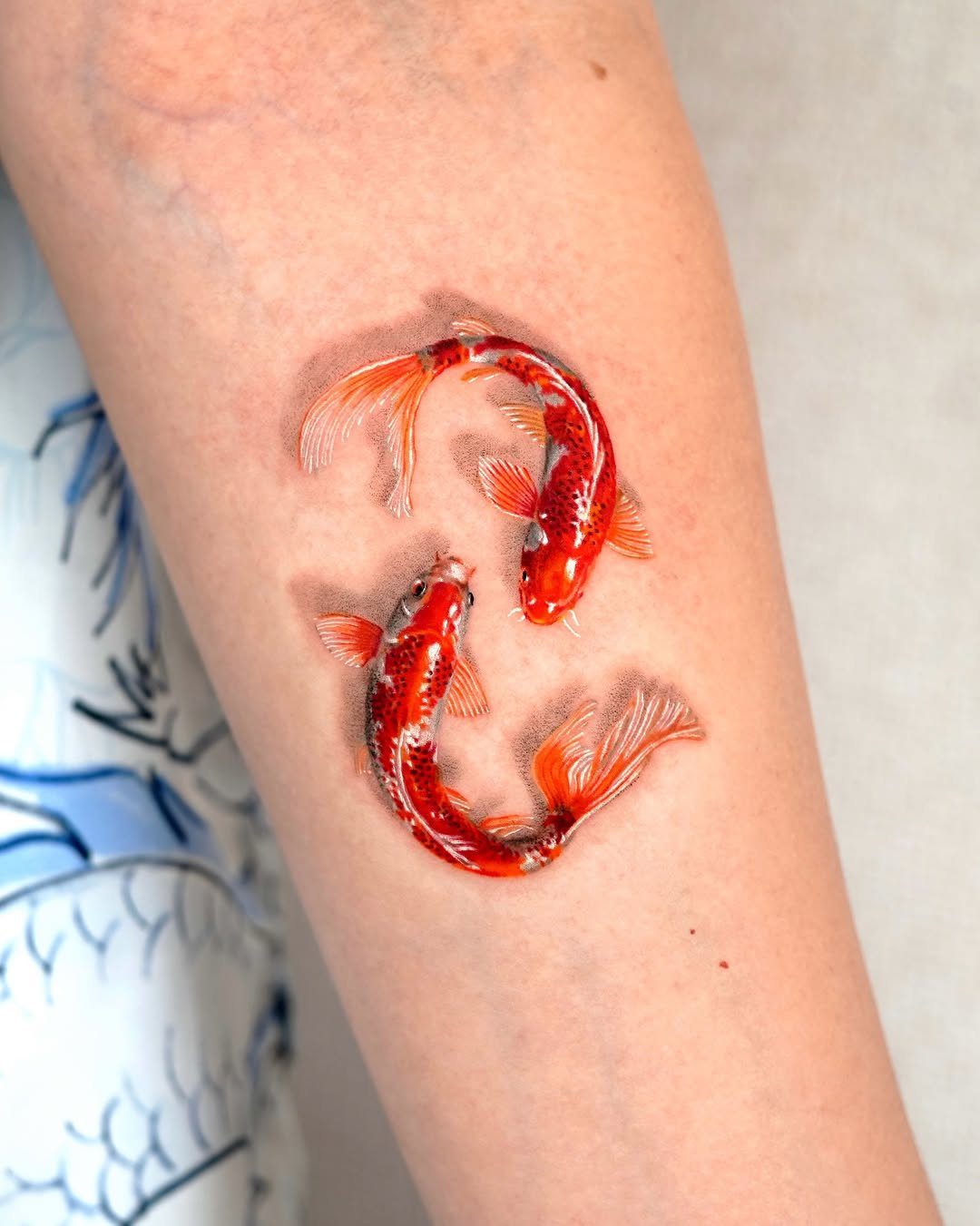 8 Red Fine Line Tattoo Ideas for Minimal Statement 3 Two realistic red and orange koi fish tattoos on a person's forearm.