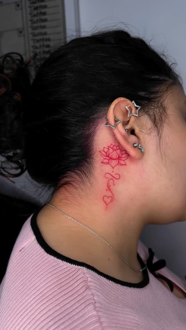 8 Red Fine Line Tattoo Ideas for Minimal Statement 7 A red fine line lotus flower tattoo with a flowing vine on a person's neck.