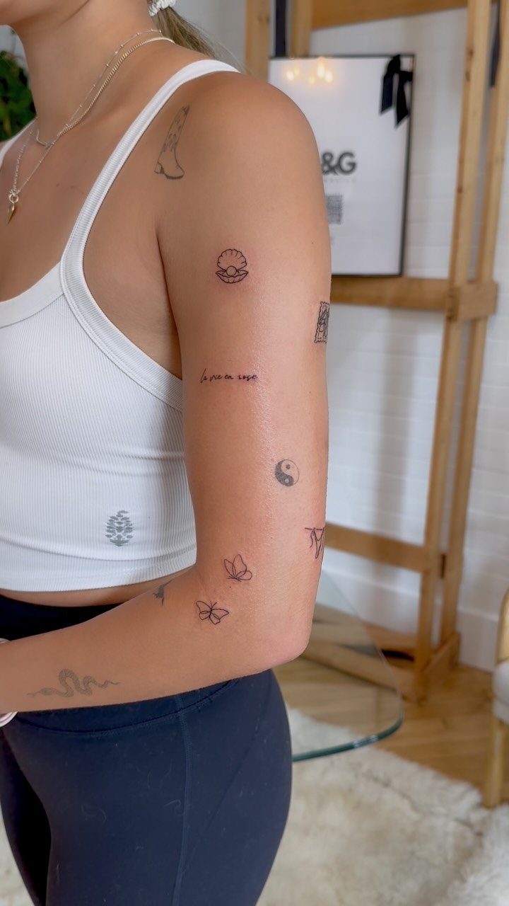 A person's arm displaying several small, simple, and elegant black ink tattoos.