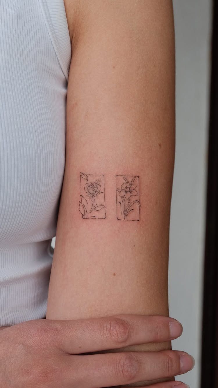 Two small fine-line floral tattoos in rectangular frames on a person's arm.