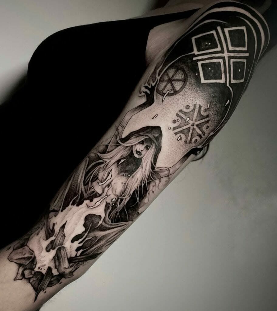 A detailed black and grey tattoo of a hooded goddess surrounded by geometric solar symbols on an arm.