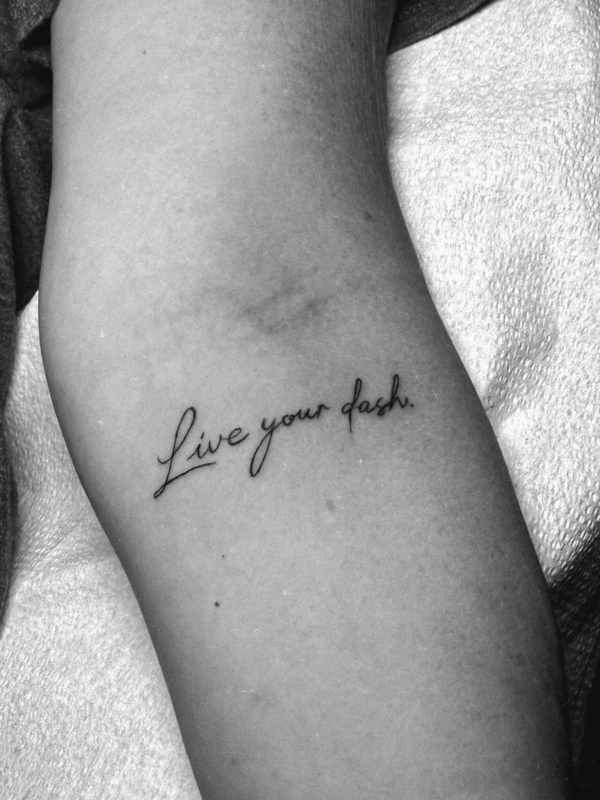 A small cursive text tattoo reading 'Live your dash' on a person's arm.
