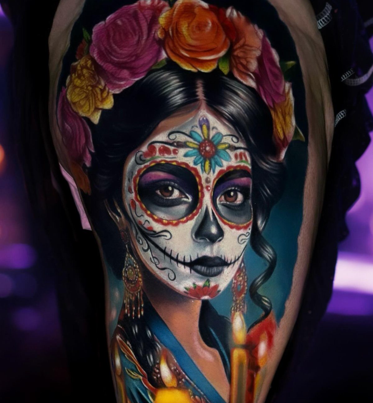 A detailed tattoo of a woman with a sugar skull face and floral crown.