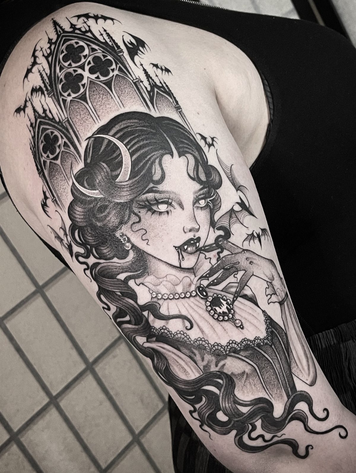 8 Tattoo Pattern Gothic Ideas: From Crows to Cathedral Arches 2 A gothic vampire woman tattoo with fangs and gothic architecture on a person's arm.