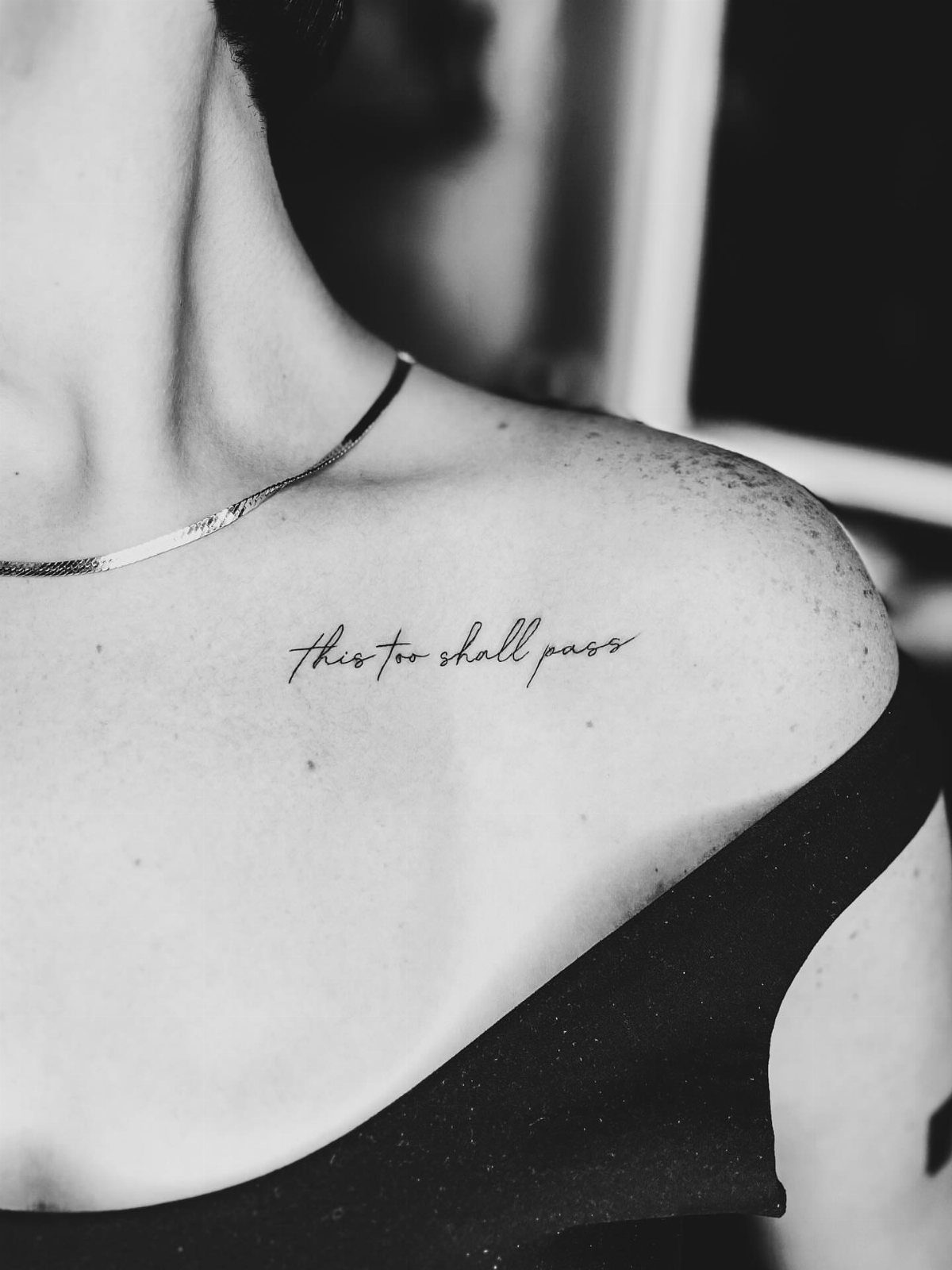 16 Word Tattoo Placement Ideas: From Spine to Finger 3 A script tattoo reading 'this too shall pass' placed on a person's collarbone.