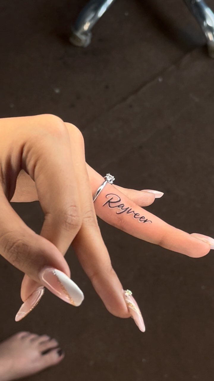 16 Word Tattoo Placement Ideas: From Spine to Finger 13 A hand with manicured nails showing a small script name tattoo on the index finger.