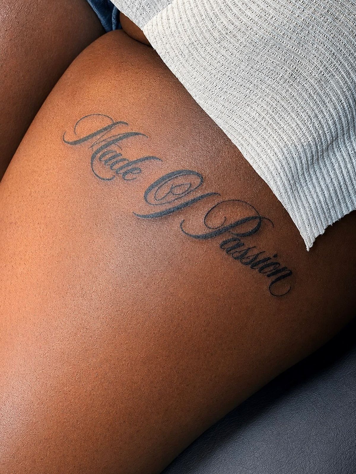 16 Word Tattoo Placement Ideas: From Spine to Finger 16 A cursive script tattoo reading 'Made Of Passion' on a person's hip.