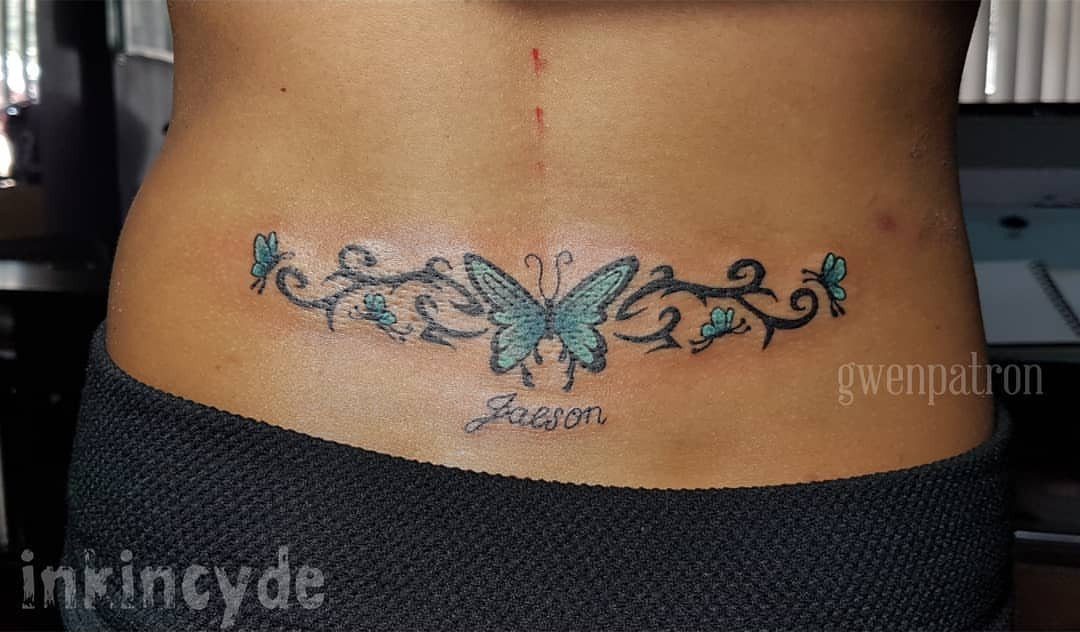 16 Word Tattoo Placement Ideas: From Spine to Finger 15 A blue butterfly and vine tattoo with the name Jaeson on a person's lower back.