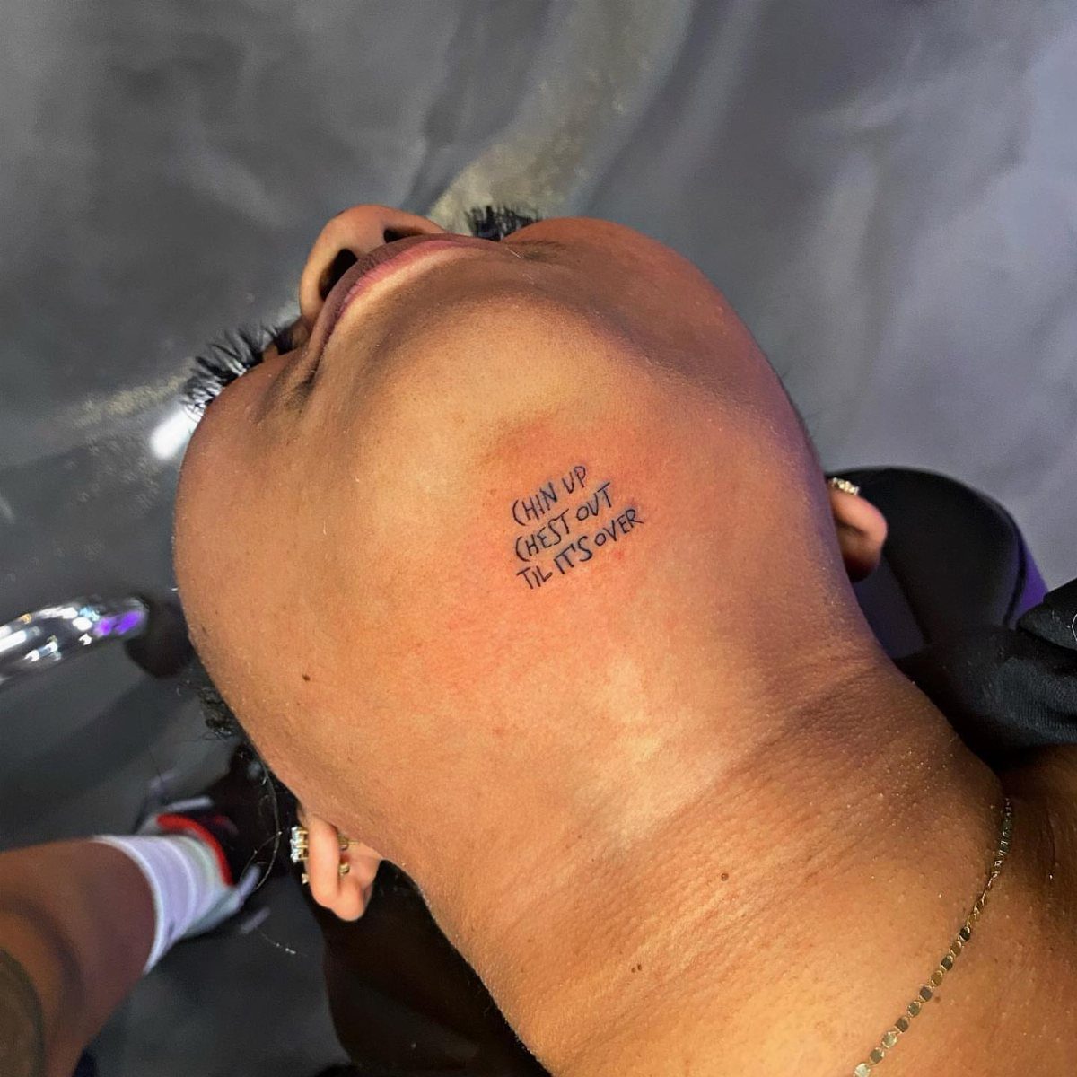 16 Word Tattoo Placement Ideas: From Spine to Finger 9 A person's neck featuring a small black text tattoo on the side.
