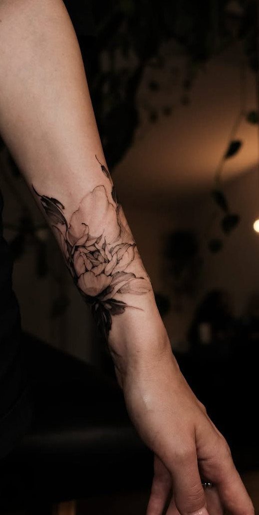 A large black and grey floral tattoo covering a person's forearm and wrist area.
