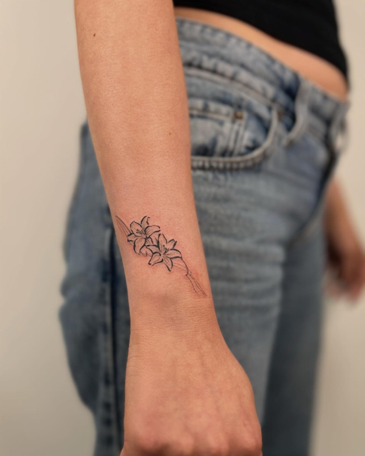 A floral lily tattoo on a person's left wrist and forearm.