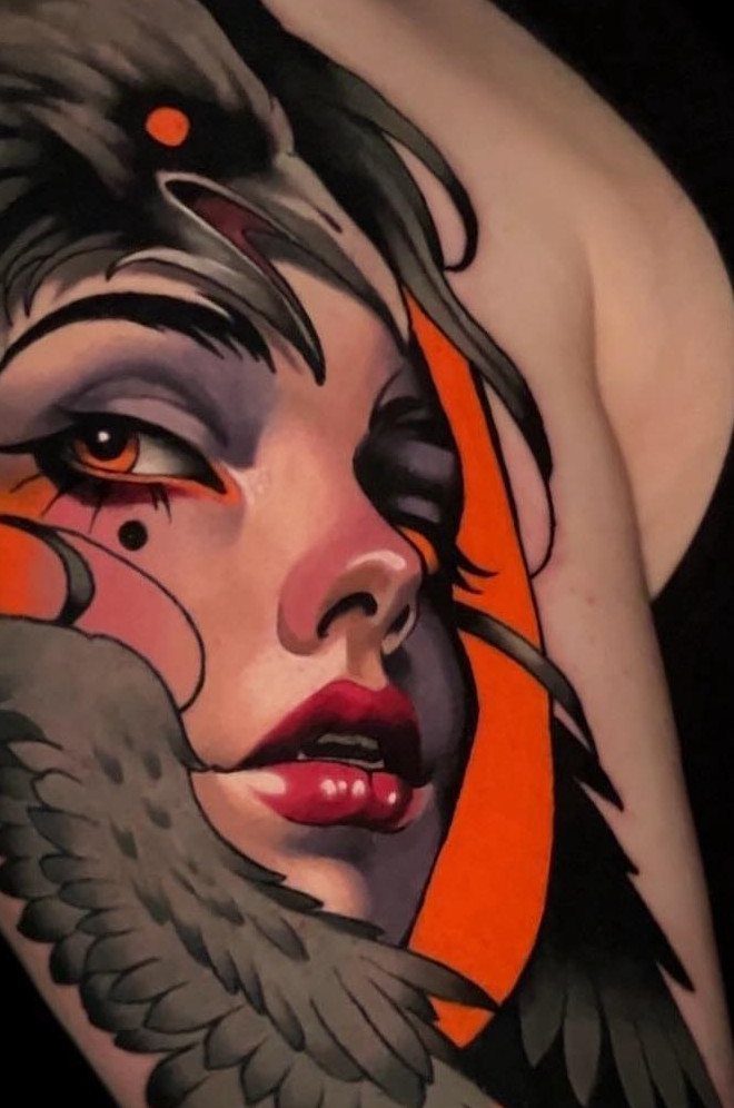 Neo-traditional tattoo of a woman's face with red lips and grey feathers on skin.