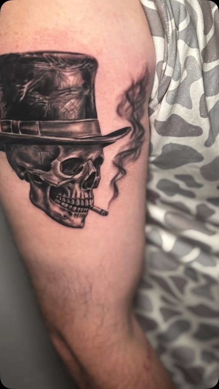 Tattoo Style Victorian: 5 Ideas From Acanthus Scrolls to Portraits 3 A black and grey tattoo of a skull wearing a top hat with smoke.