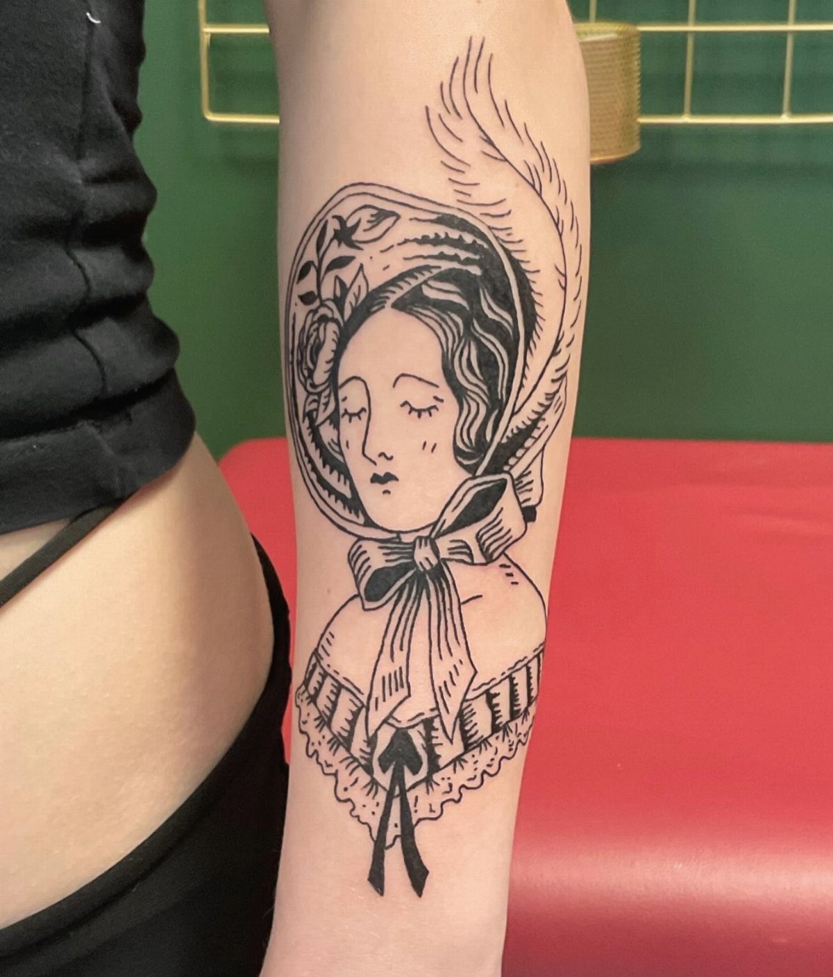Tattoo Style Victorian: 5 Ideas From Acanthus Scrolls to Portraits 5 A black ink tattoo of a Victorian lady wearing a feathered bonnet on a forearm.