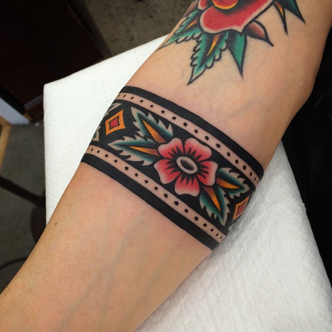 8 Traditional Tattoo Cuff Ideas for Wrists and Forearms 2 A colorful American traditional style tattoo band wrapping around a person's forearm.