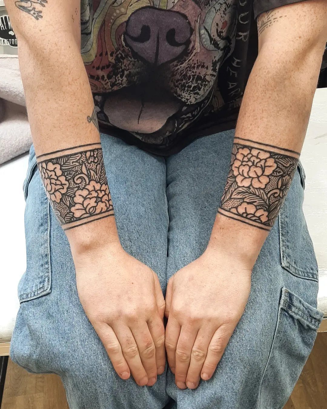 8 Traditional Tattoo Cuff Ideas for Wrists and Forearms 8 Two forearms featuring matching black ink traditional floral tattoo cuffs on the wrists.